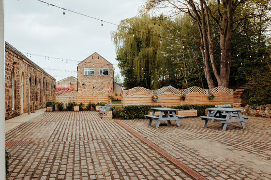 Courtyard area of The Venue, Eskmills, decorated with picnic tables and hanging baskets